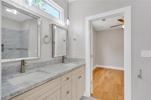 6100 Duplessis St, New Orleans, LA 70122 - bathroom featuring double vanity, wood finished floors, ceiling fan, a tile shower, and baseboards