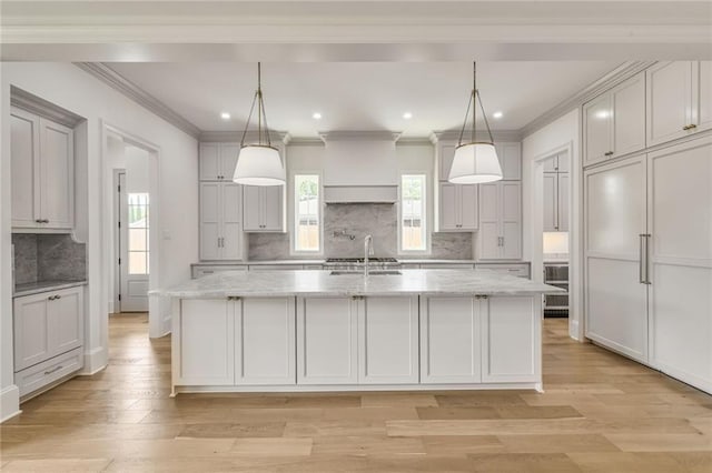 7331 Onyx St, New Orleans, LA 70124 - kitchen with a large island with sink, decorative backsplash, light stone counters, light wood finished floors, and recessed lighting