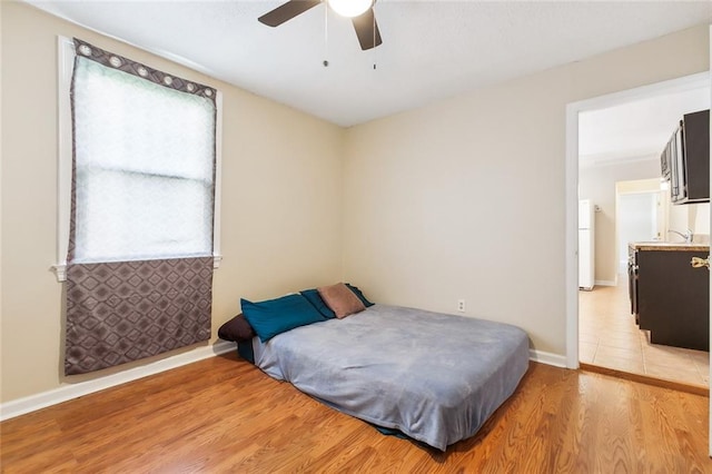 3309 4th St, New Orleans, LA 70125 - bedroom featuring light wood-style flooring, freestanding refrigerator, a ceiling fan, and baseboards