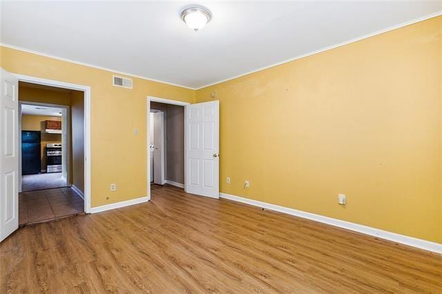 3309 4th St, New Orleans, LA 70125 - unfurnished bedroom with light wood finished floors, baseboards, fridge, and ornamental molding