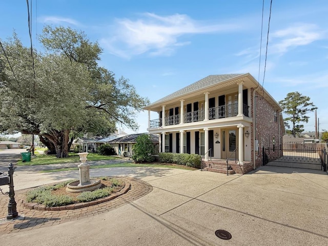 9125 5th St, River Ridge, LA 70123 - view of front of property with curved driveway, a balcony, a gate, a porch, and brick siding