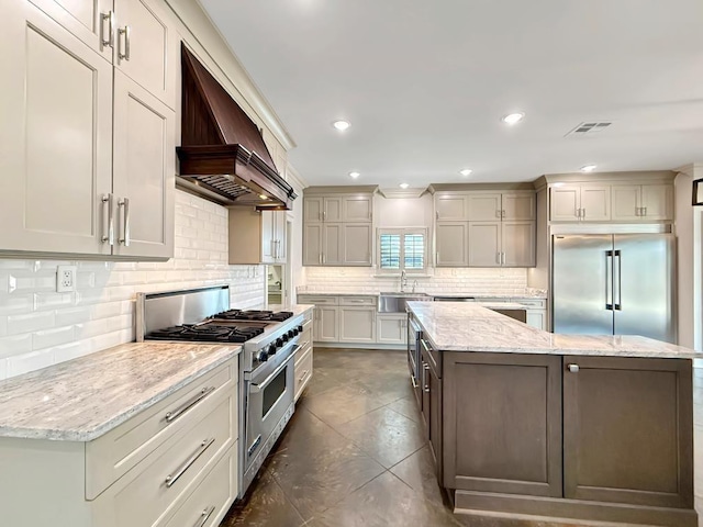 9125 5th St, River Ridge, LA 70123 - kitchen with high quality appliances, premium range hood, a kitchen island, a sink, and decorative backsplash