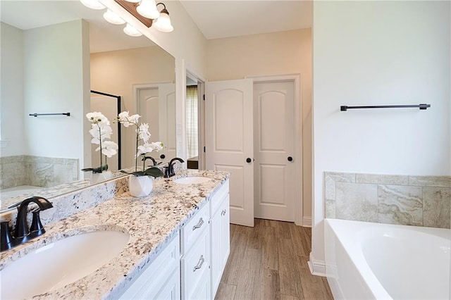 229 Louisiana Iris Cir, Slidell, LA 70458 - bathroom featuring a garden tub, wood finished floors, baseboards, and double vanity