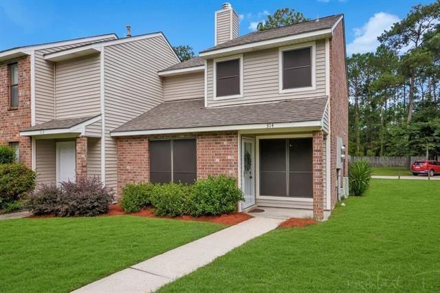 314 E Pineridge St Unit 314, Mandeville, LA 70448 - view of front of home featuring brick siding, a front lawn, a chimney, and a shingled roof
