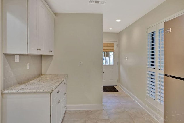 314 E Pineridge St Unit 314, Mandeville, LA 70448 - kitchen with freestanding refrigerator, tasteful backsplash, baseboards, white cabinets, and light stone counters