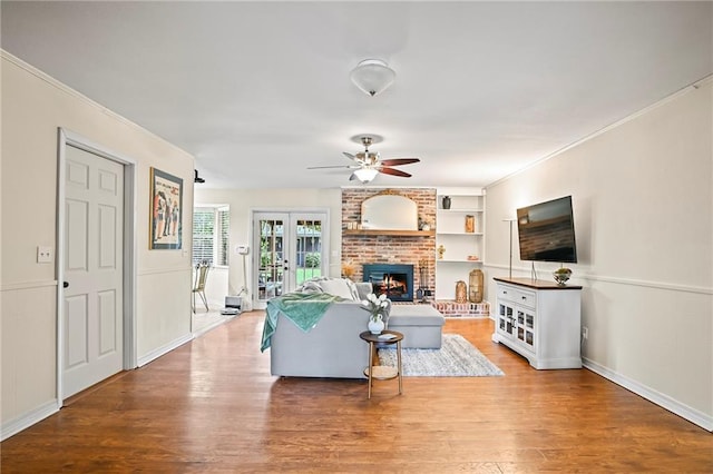 1532 Broadmoor Dr, Slidell, LA 70458 - living room featuring a ceiling fan, wood finished floors, a fireplace, french doors, and crown molding