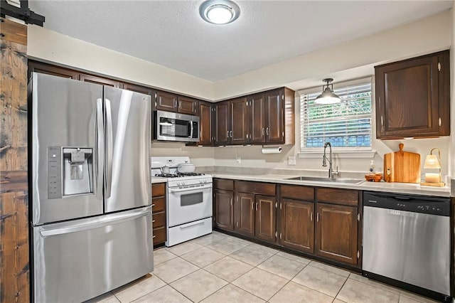 1532 Broadmoor Dr, Slidell, LA 70458 - kitchen featuring stainless steel appliances, a sink, light countertops, light tile patterned floors, and dark brown cabinetry