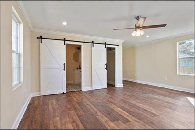921 Andry St, New Orleans, LA 70117 - unfurnished bedroom featuring ornamental molding, a barn door, wood finished floors, baseboards, and recessed lighting