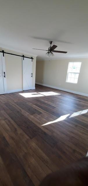 921 Andry St, New Orleans, LA 70117 - unfurnished room featuring a barn door, dark wood finished floors, baseboards, and a ceiling fan