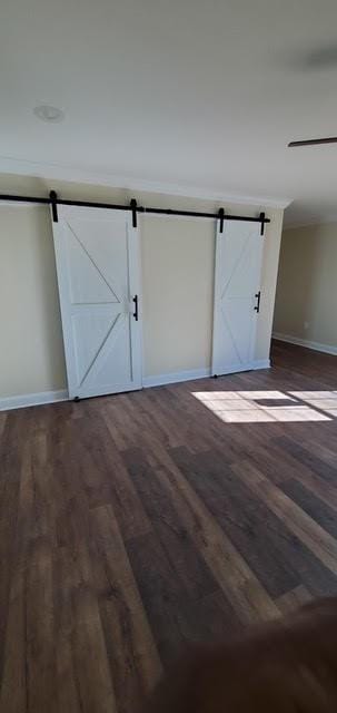 921 Andry St, New Orleans, LA 70117 - unfurnished bedroom featuring a barn door, baseboards, and dark wood-style flooring