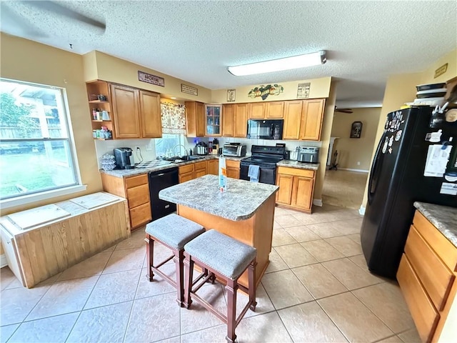 112 Cedarwood Dr, Slidell, LA 70461 - kitchen with black appliances, plenty of natural light, a breakfast bar, a kitchen island, and a textured ceiling