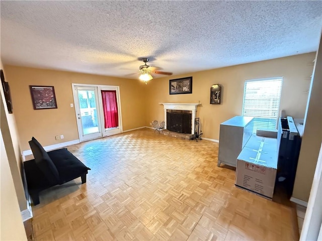 112 Cedarwood Dr, Slidell, LA 70461 - living room with a textured ceiling, a ceiling fan, a fireplace with raised hearth, and baseboards