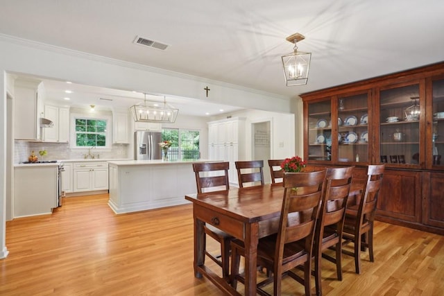 42 Riverdale Dr, Covington, LA 70433 - dining room featuring light wood-type flooring, ornamental molding, and a chandelier