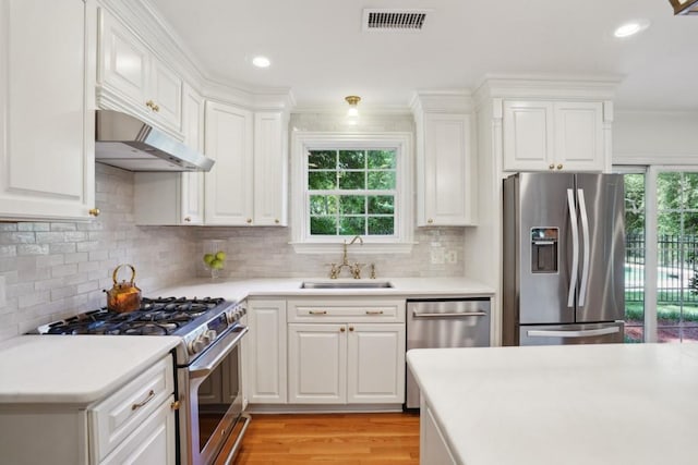 42 Riverdale Dr, Covington, LA 70433 - kitchen with stainless steel appliances, a sink, under cabinet range hood, light wood finished floors, and light countertops