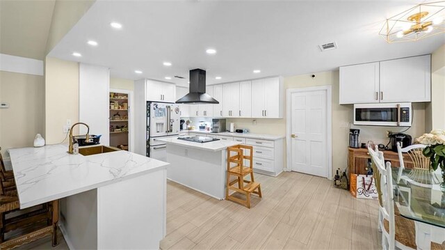 61258 N Military Rd, Slidell, LA 70461 - kitchen featuring island exhaust hood, a kitchen bar, a sink, a peninsula, and recessed lighting