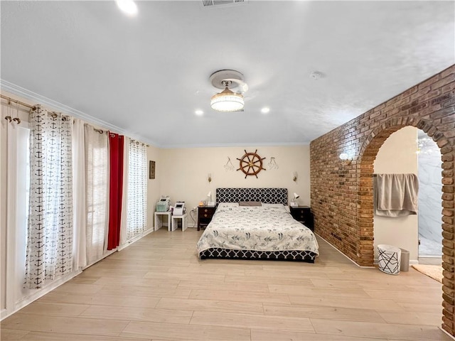 61258 N Military Rd, Slidell, LA 70461 - bedroom featuring brick wall, light wood-style floors, arched walkways, crown molding, and baseboards