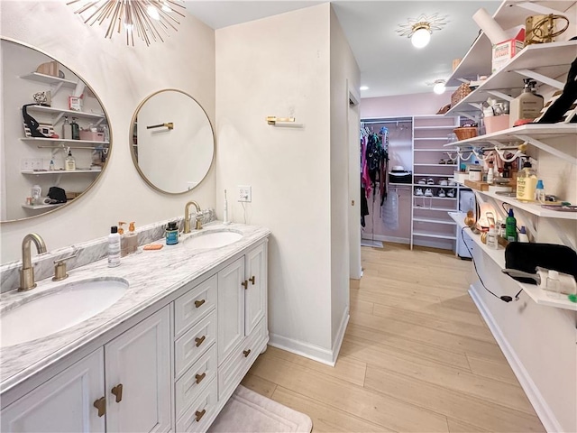 61258 N Military Rd, Slidell, LA 70461 - bathroom featuring wood finished floors, a chandelier, double vanity, baseboards, and a walk in closet