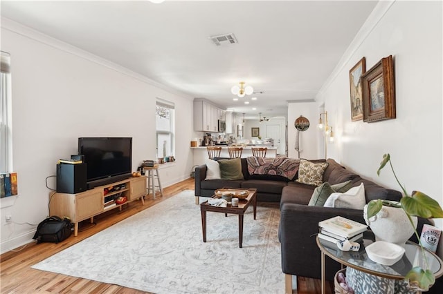 1101 Fairway Dr, Kenner, LA 70062 - living room with crown molding, light wood-style floors, baseboards, and a chandelier
