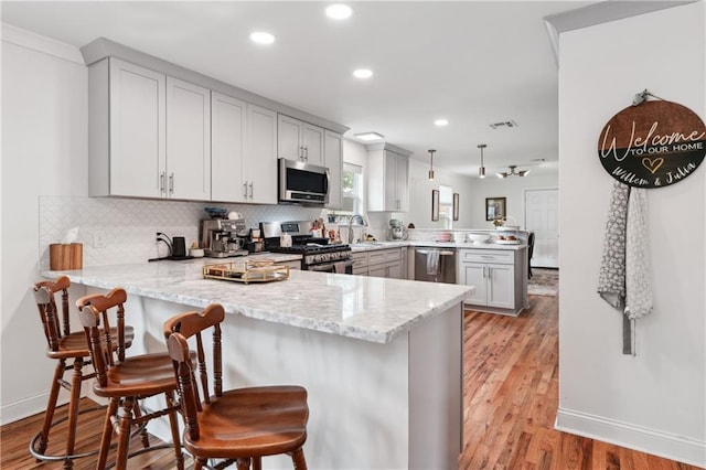1101 Fairway Dr, Kenner, LA 70062 - kitchen featuring stainless steel appliances, a peninsula, a sink, light wood-type flooring, and recessed lighting