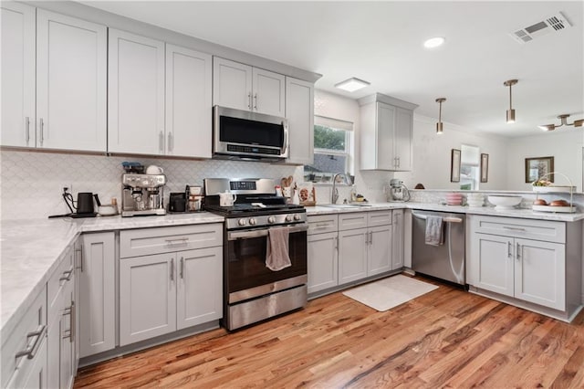 1101 Fairway Dr, Kenner, LA 70062 - kitchen featuring appliances with stainless steel finishes, a sink, a peninsula, light wood-style floors, and ornamental molding