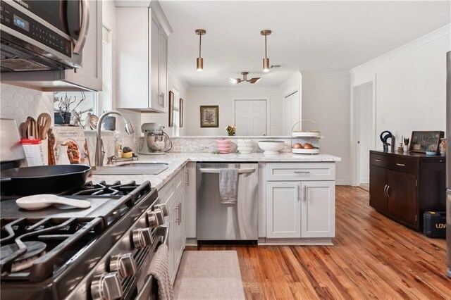 1101 Fairway Dr, Kenner, LA 70062 - kitchen featuring appliances with stainless steel finishes, a peninsula, a sink, light wood-style floors, and crown molding