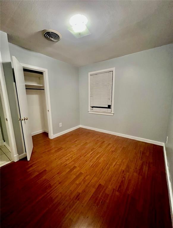 2228 Kentucky Ave, Kenner, LA 70062 - unfurnished bedroom featuring wood finished floors, baseboards, and a closet