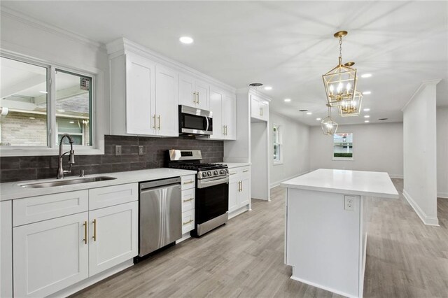 3313 Clifford Dr, Metairie, LA 70002 - kitchen with stainless steel appliances, a sink, decorative backsplash, white cabinetry, and a kitchen island