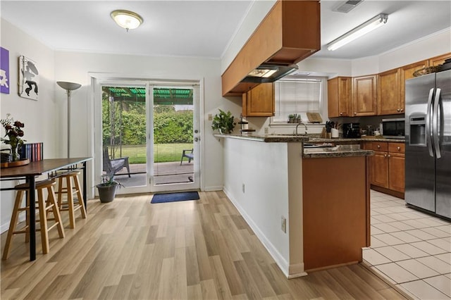 2529 Hudson Pl, New Orleans, LA 70131 - kitchen featuring stainless steel appliances, brown cabinetry, crown molding, light wood-style flooring, and a peninsula