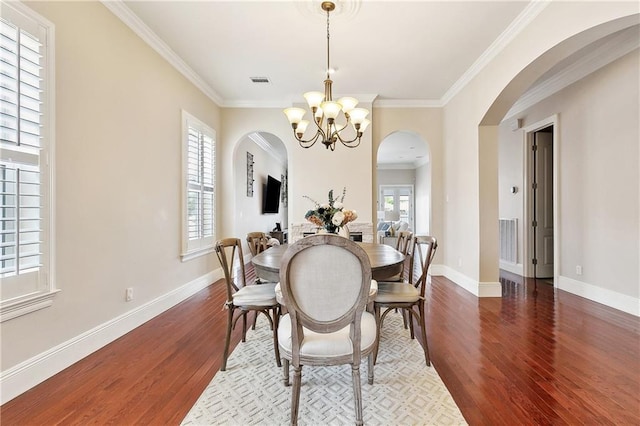 6919 Memphis St, New Orleans, LA 70124 - dining area with arched walkways, wood finished floors, a chandelier, ornamental molding, and baseboards