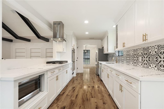 25 Woodvine Ct, Covington, LA 70433 - kitchen with island exhaust hood, appliances with stainless steel finishes, white cabinetry, backsplash, and wood finished floors