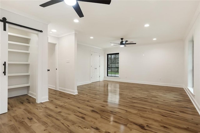 25 Woodvine Ct, Covington, LA 70433 - unfurnished living room with ceiling fan, a barn door, crown molding, wood finished floors, and baseboards