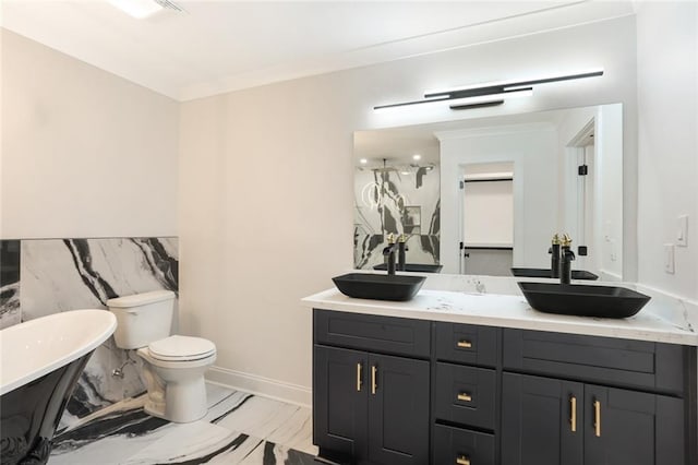 25 Woodvine Ct, Covington, LA 70433 - full bathroom featuring a freestanding tub, double vanity, marble look tiles, toilet, and a wainscoted wall