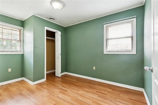 2412 Riverbend Dr, Violet, LA 70092 - unfurnished bedroom with ornamental molding, light wood-style floors, baseboards, and a closet