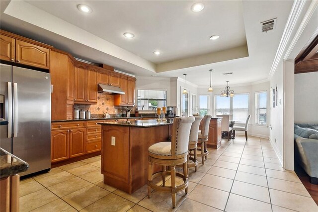 101 Gretel Cv, Slidell, LA 70458 - kitchen featuring stainless steel fridge with ice dispenser, under cabinet range hood, a kitchen bar, plenty of natural light, and ornamental molding
