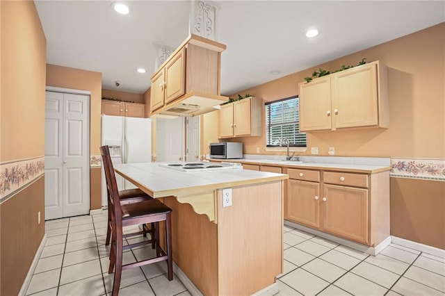 70408 7th St, Covington, LA 70433 - kitchen featuring stainless steel microwave, light brown cabinetry, tile counters, white electric stovetop, and a sink