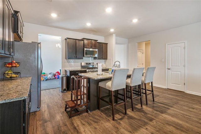 521 Lakeshore Village Ln, Slidell, LA 70461 - kitchen with stainless steel appliances, dark wood finished floors, a breakfast bar area, an island with sink, and dark brown cabinetry