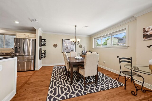 3425 Vincennes Pl, New Orleans, LA 70125 - dining room featuring baseboards, light wood-style floors, a chandelier, and crown molding