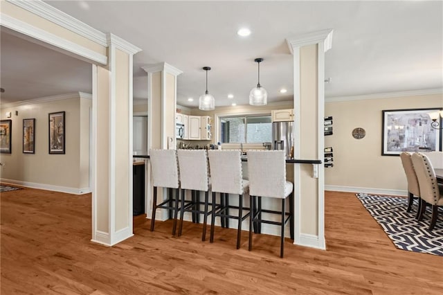 3425 Vincennes Pl, New Orleans, LA 70125 - kitchen featuring a kitchen breakfast bar, baseboards, light wood-style flooring, stainless steel refrigerator with ice dispenser, and ornamental molding