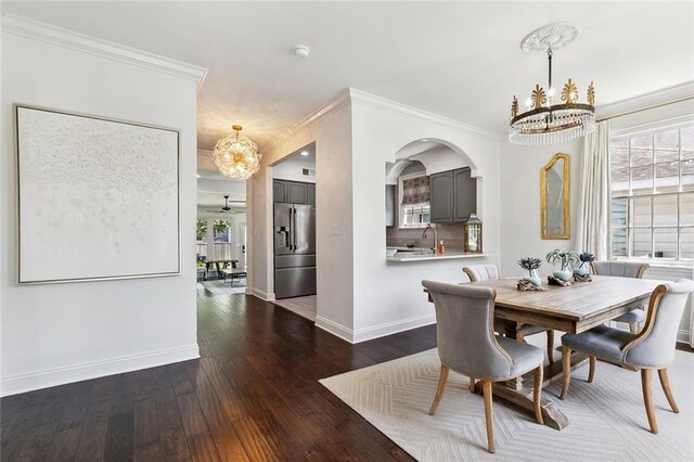 6951 Memphis St, New Orleans, LA 70124 - dining space with a chandelier, crown molding, wood-type flooring, baseboards, and arched walkways