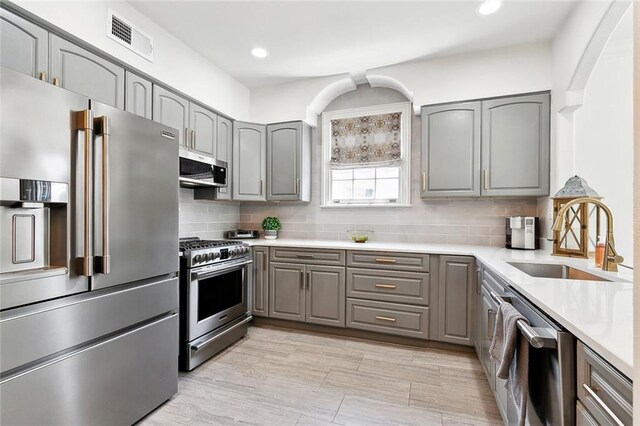 6951 Memphis St, New Orleans, LA 70124 - kitchen featuring high quality appliances, gray cabinets, a sink, decorative backsplash, and light countertops