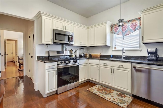 2409-11 St Ann St, New Orleans, LA 70119 - kitchen featuring stainless steel appliances, a sink, dark wood-style floors, and hanging light fixtures