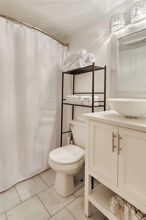 2409-11 St Ann St, New Orleans, LA 70119 - full bath with vanity, toilet, a shower with shower curtain, and marble finish floors