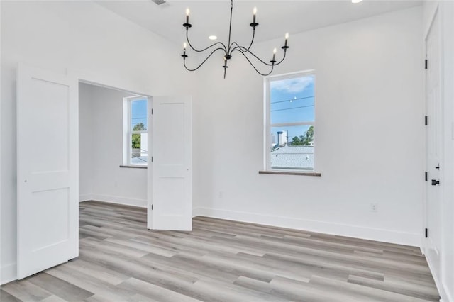 330103 S Saratoga St, New Orleans, LA 70115 - unfurnished dining area with a chandelier, light wood-type flooring, and baseboards