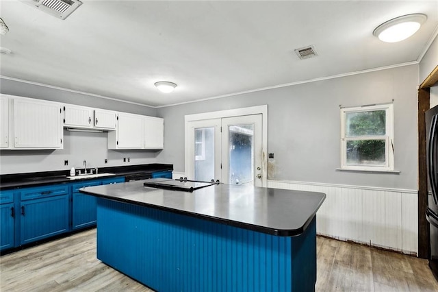 72430 Bullard St, Covington, LA 70435 - kitchen featuring blue cabinets, dark countertops, light wood-type flooring, ornamental molding, and white cabinets