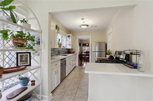 4462 Lafaye St, New Orleans, LA 70122 - kitchen featuring appliances with stainless steel finishes, decorative backsplash, white cabinetry, light tile patterned floors, and a sink