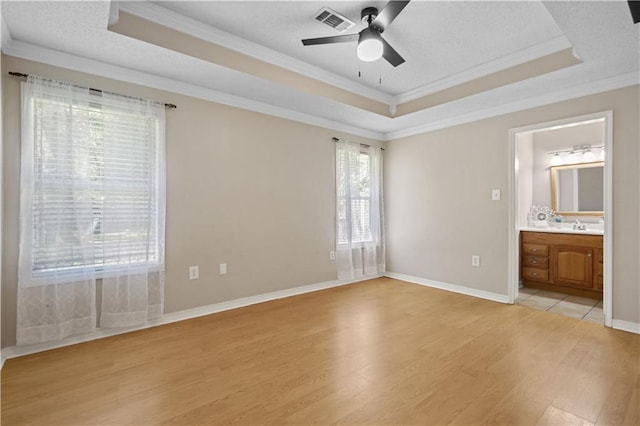 101 Sugar Mill Dr, Slidell, LA 70458 - unfurnished bedroom featuring a raised ceiling, light wood finished floors, ornamental molding, a textured ceiling, and ensuite bath