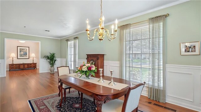 5000 Senac Dr, Metairie, LA 70003 - dining space with a chandelier, wainscoting, ornamental molding, a decorative wall, and wood finished floors