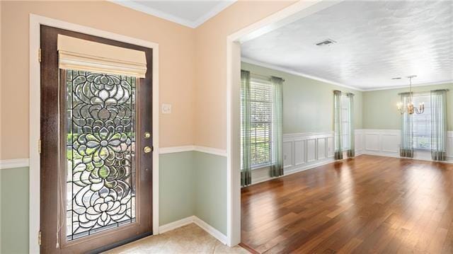 5000 Senac Dr, Metairie, LA 70003 - entrance foyer featuring a chandelier, ornamental molding, wood finished floors, and wainscoting