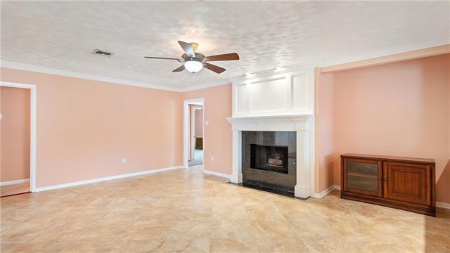 5000 Senac Dr, Metairie, LA 70003 - unfurnished living room featuring ceiling fan, a fireplace, ornamental molding, and baseboards