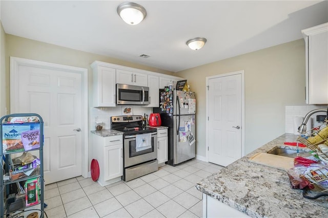 711921 Marshal Foch St, New Orleans, LA 70124 - kitchen featuring appliances with stainless steel finishes, decorative backsplash, white cabinets, a sink, and light tile patterned flooring